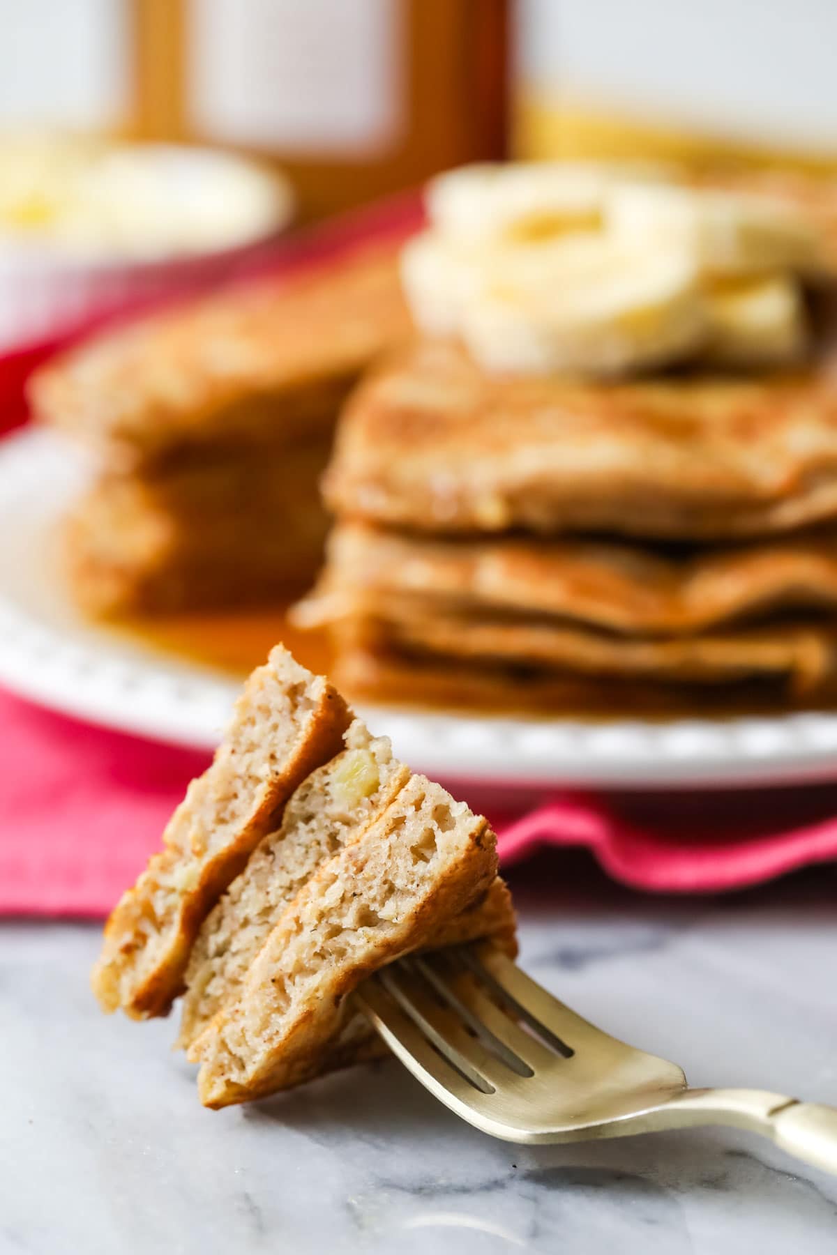 Fork with a bite from a stack of pancakes.