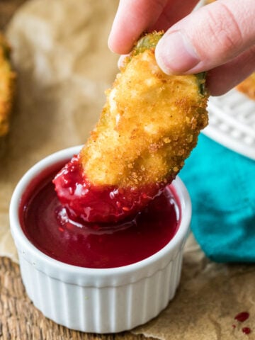 Jalapeno popper being dipped into a raspberry dipping sauce.