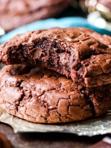 Two brownie cookies stacked on top of each other with the top cookie missing a bite.