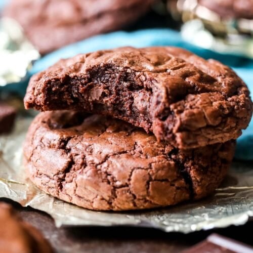 Two brownie cookies stacked on top of each other with the top cookie missing a bite.