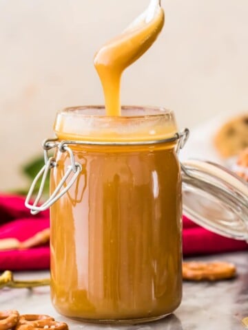 golden caramel sauce dripping off spoon into glass container