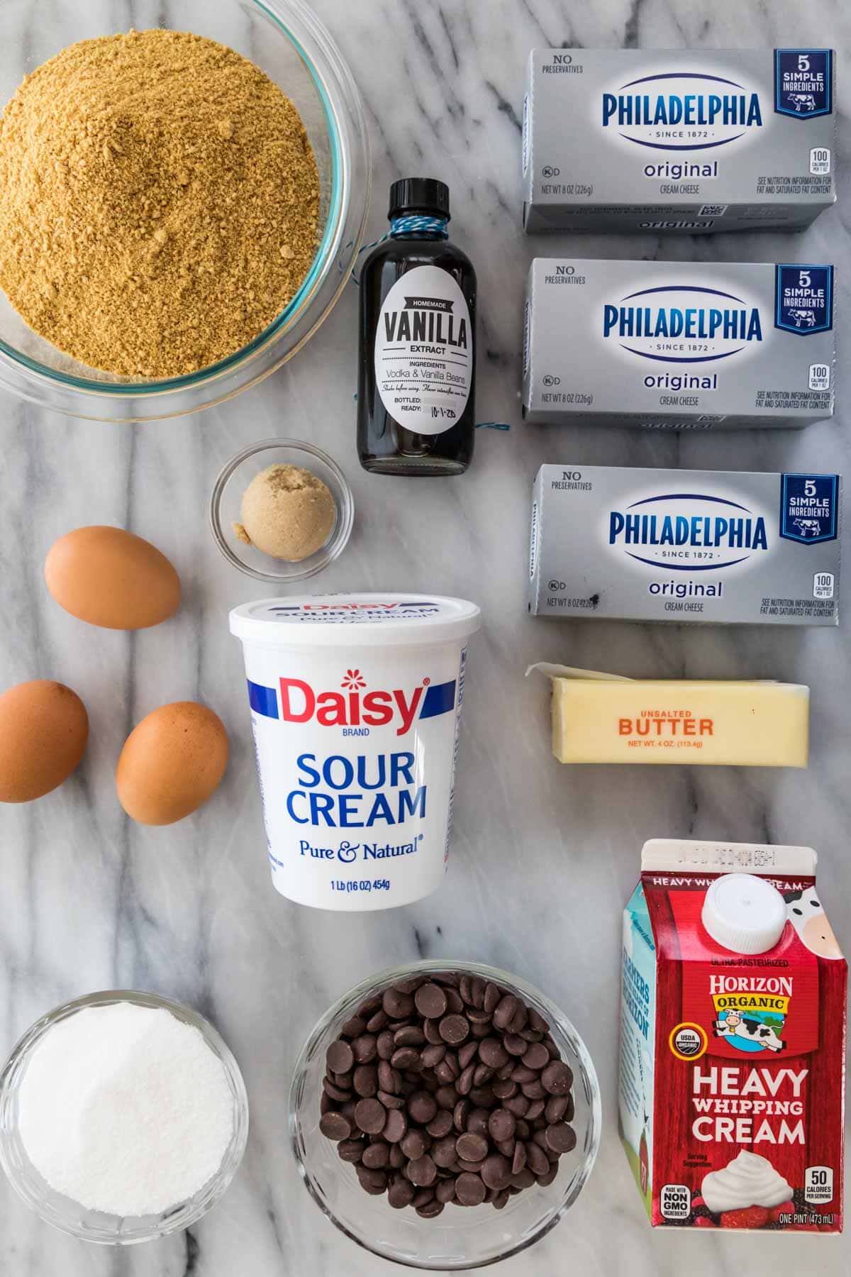 overhead view of ingredients including cream cheese, graham cracker crumbs, vanilla extract, and more