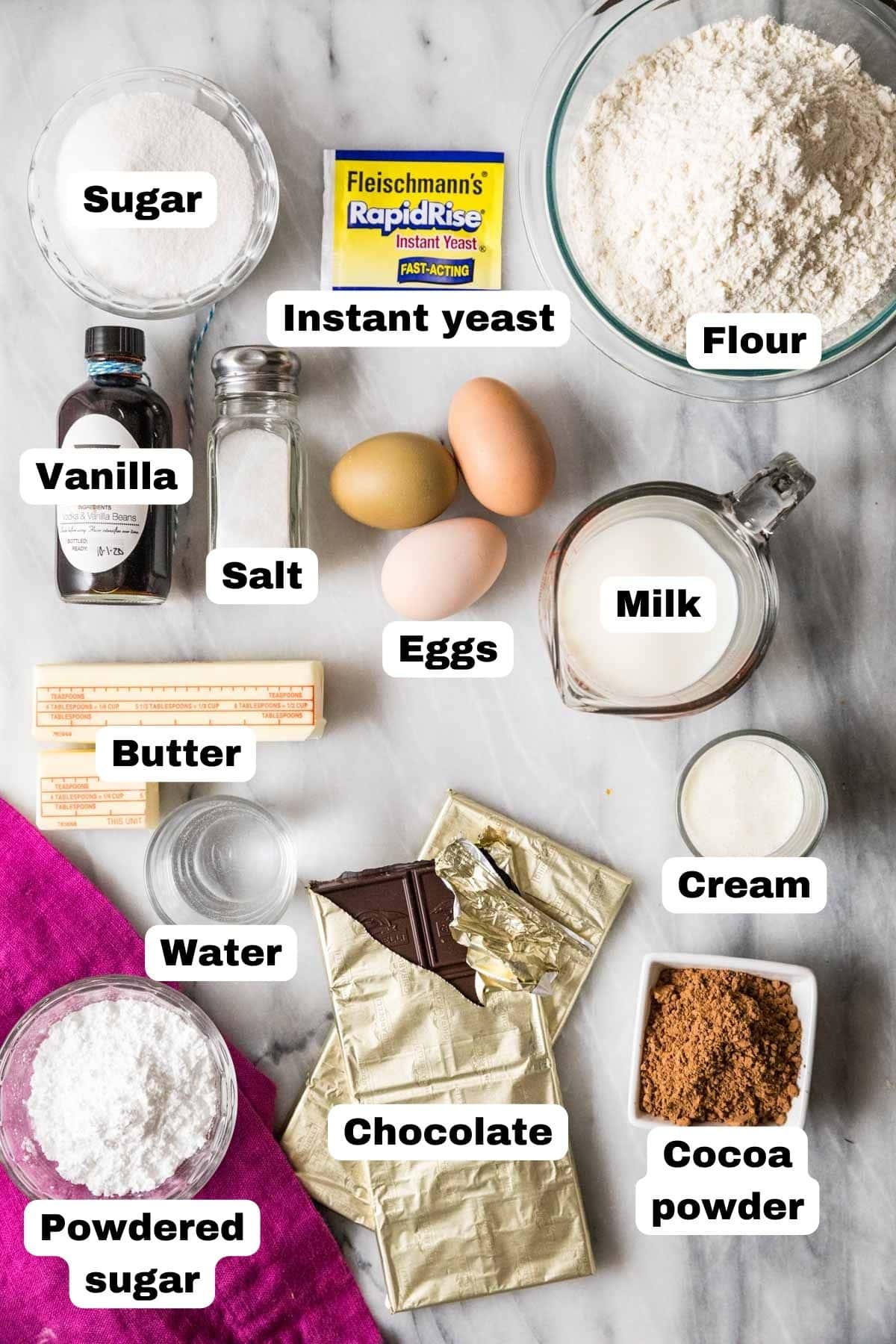 Overhead view of labelled ingredients including yeast, chocolate, cocoa powder, and more.