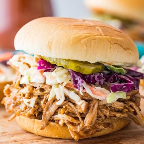 instant pot pulled pork on a sandwich topped with homemade coleslaw and pickles