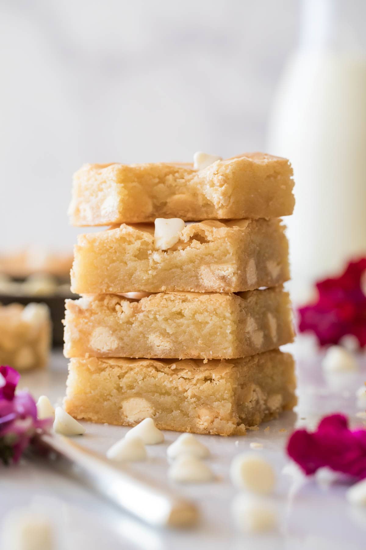 Four white chocolate brownies stacked on top of each other with the top brownie missing one bite.