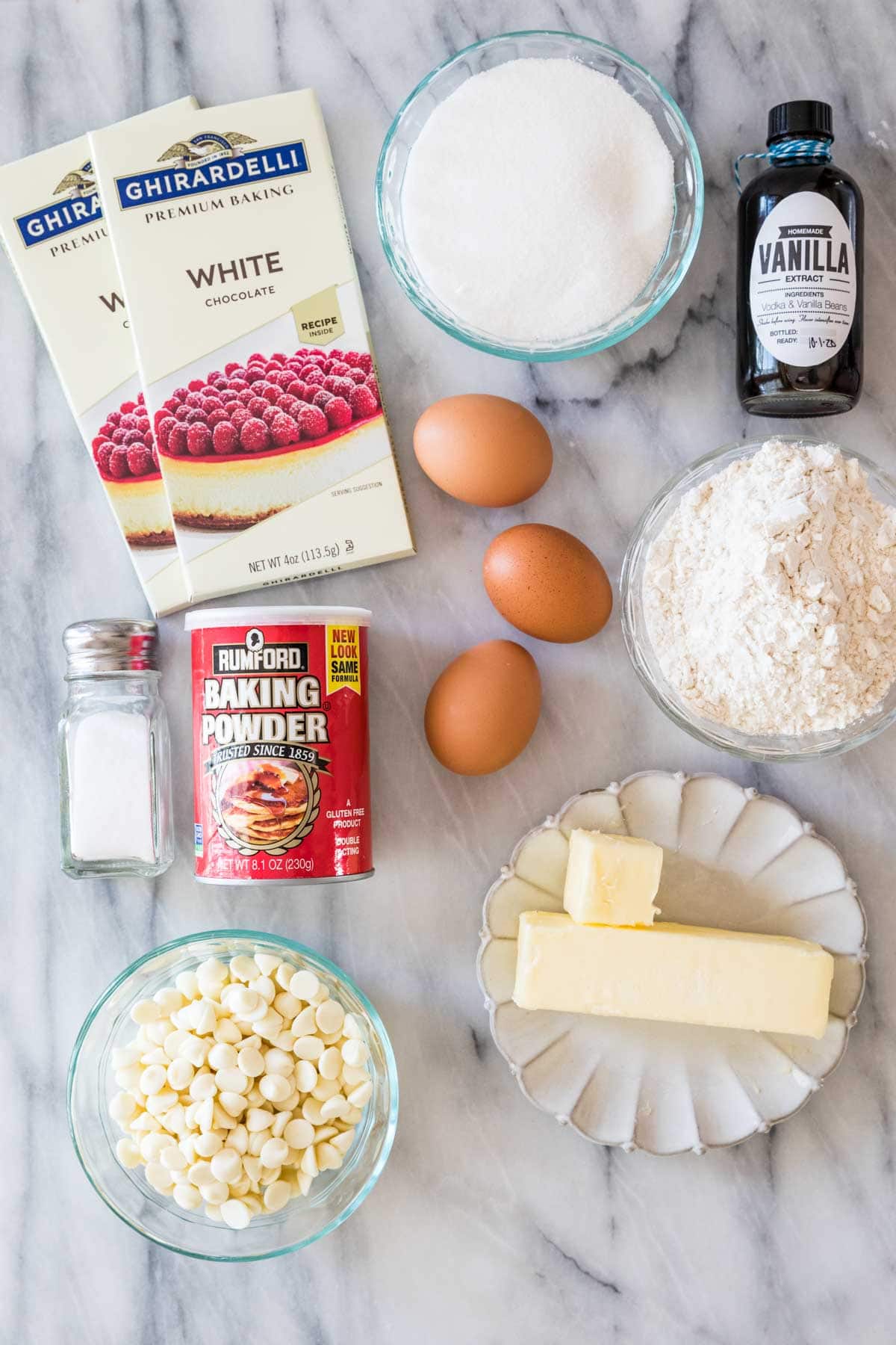 Overhead view of ingredients including white chocolate, eggs, vanilla, butter, and more.