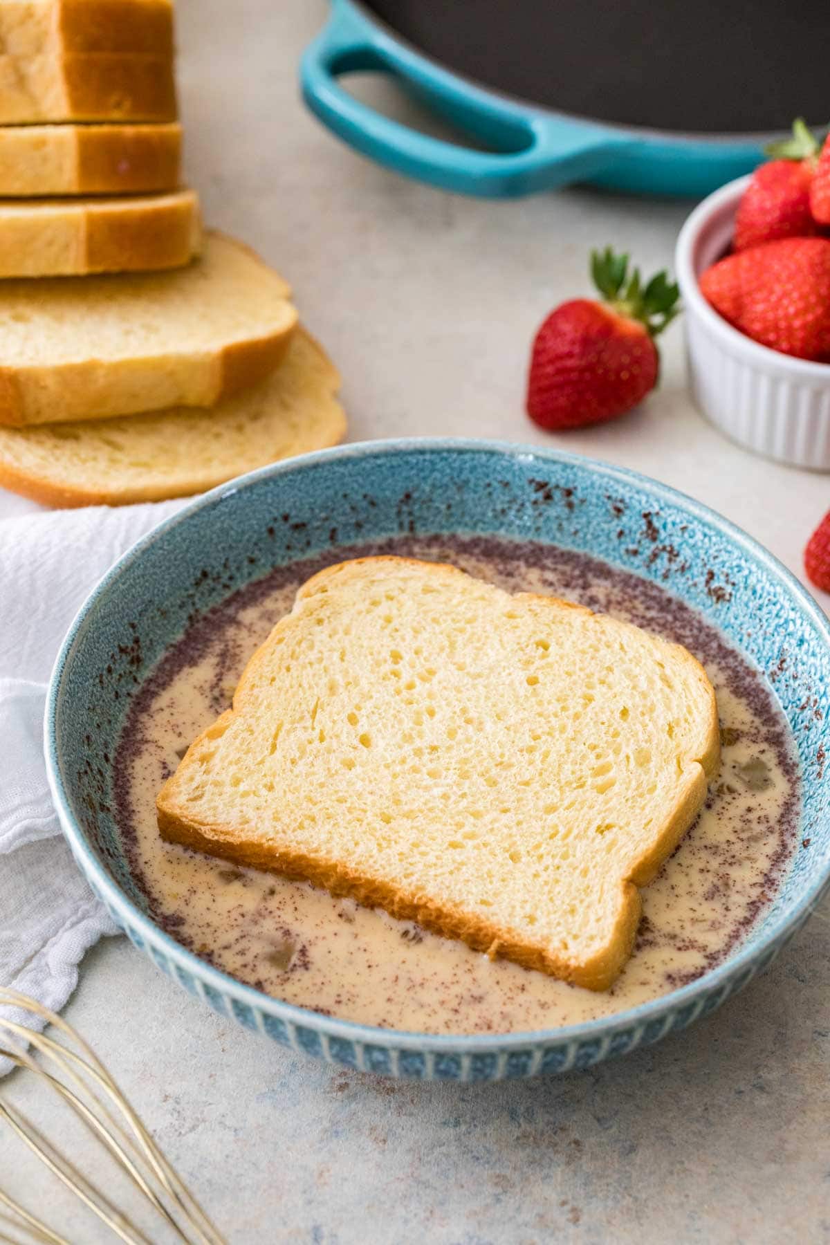 Slice of bread soaking up a cinnamon custard mixture.