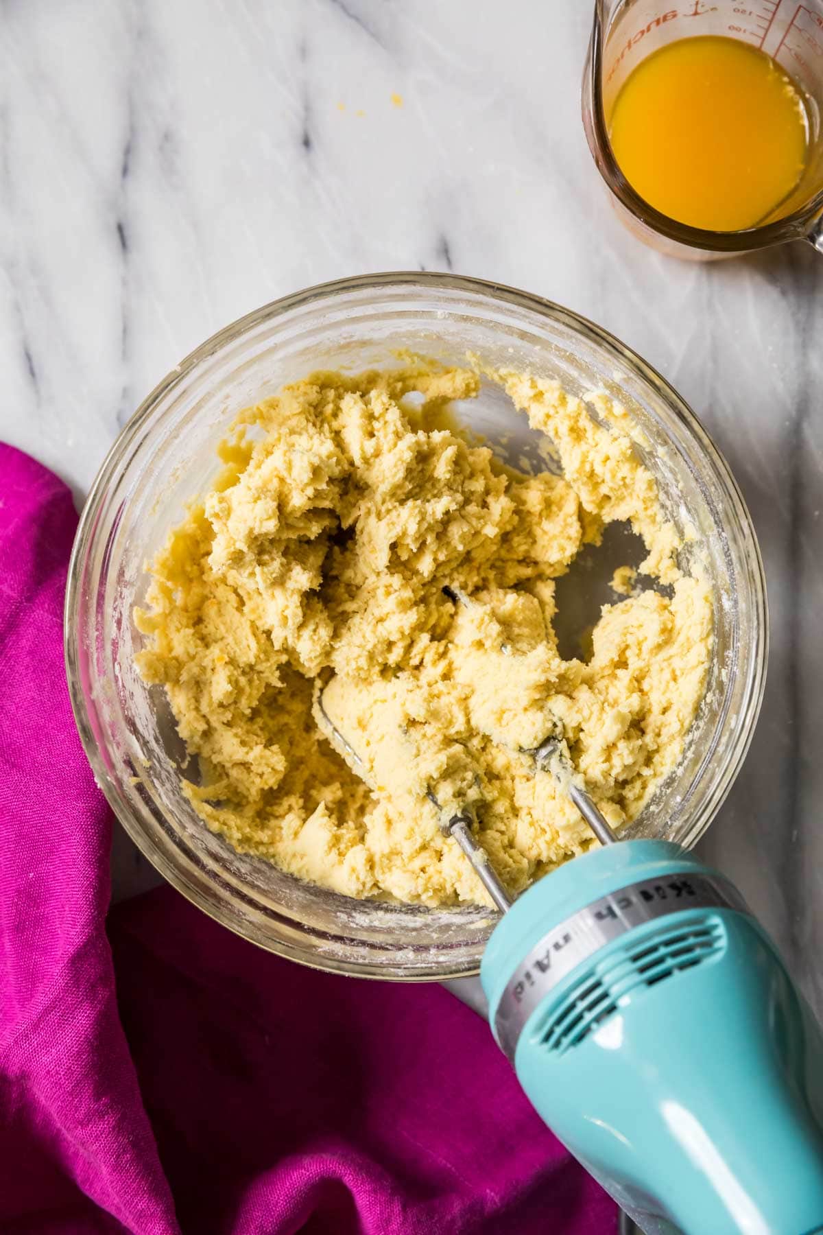 Overhead view of cookie dough being mixed with an electric hand mixer.