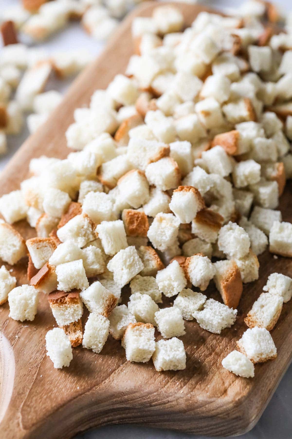 Close-up view of homemade bread cubes on a wood cutting board.