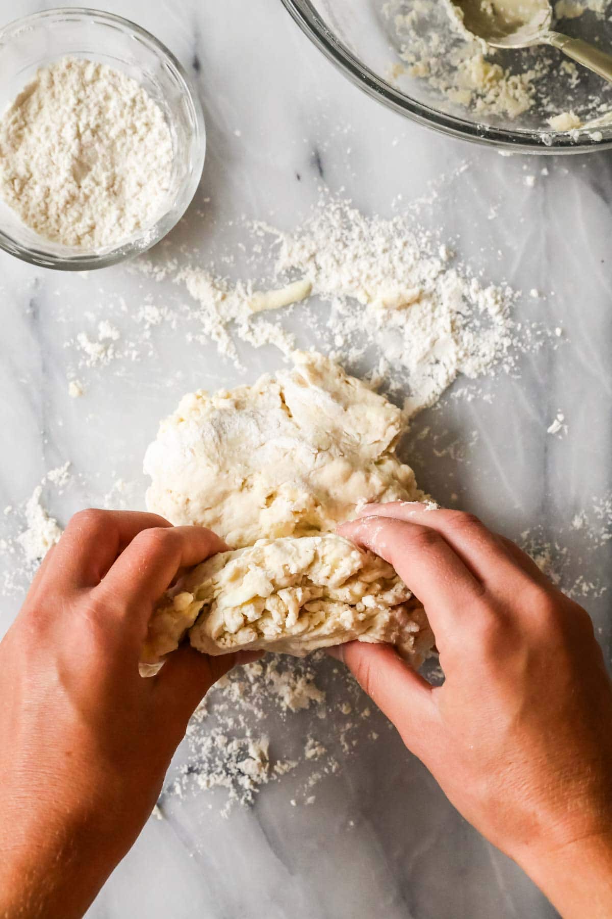 Hands folding biscuit dough over itself for laminatino.