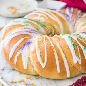 golden brown king cake frosted with white icing and sprinkled with colorful sanding sugars