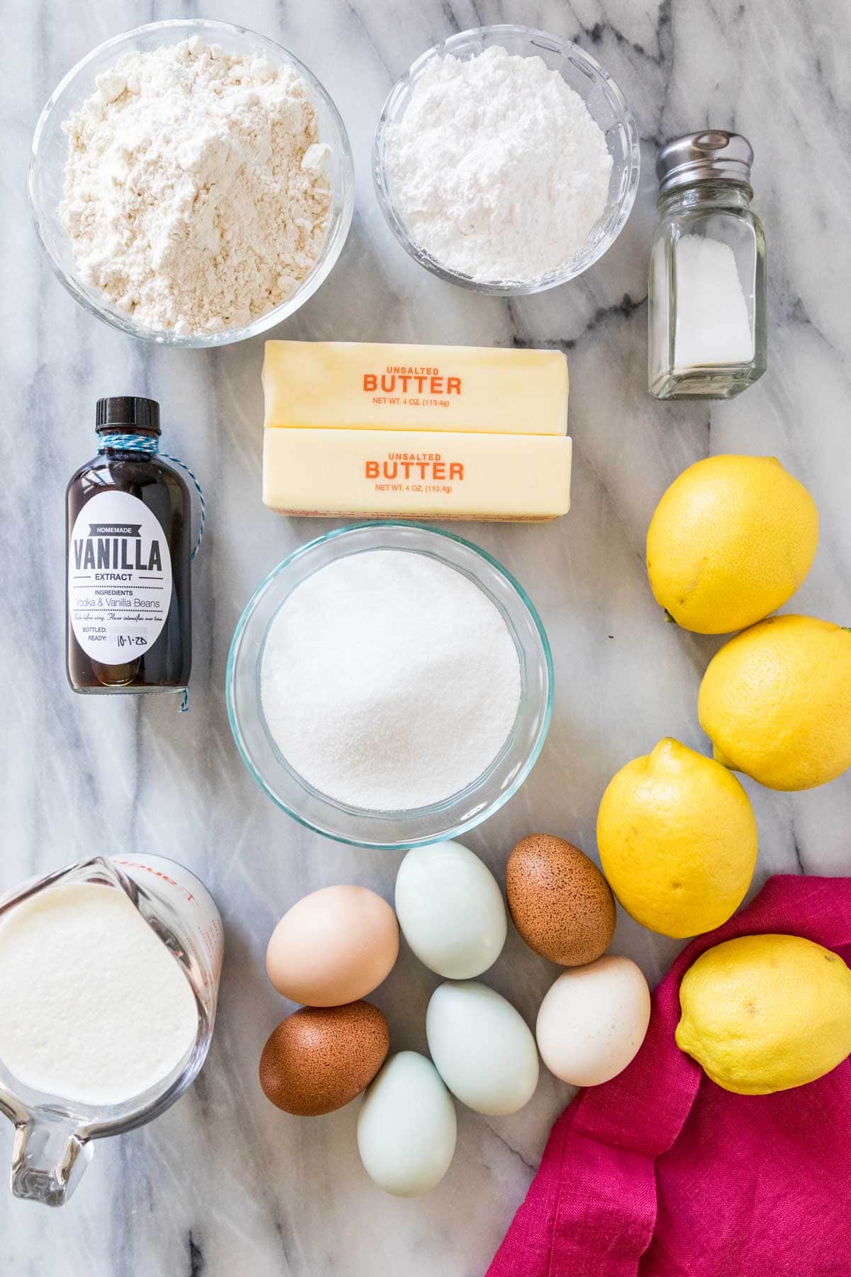 Overhead view of ingredients including lemons, eggs, sugar, butter, and more.