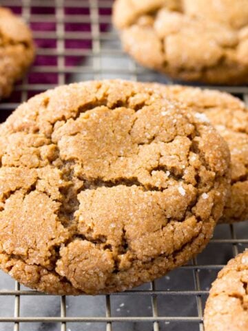 Crackly topped molasses cookies on a cooling rack after baking.