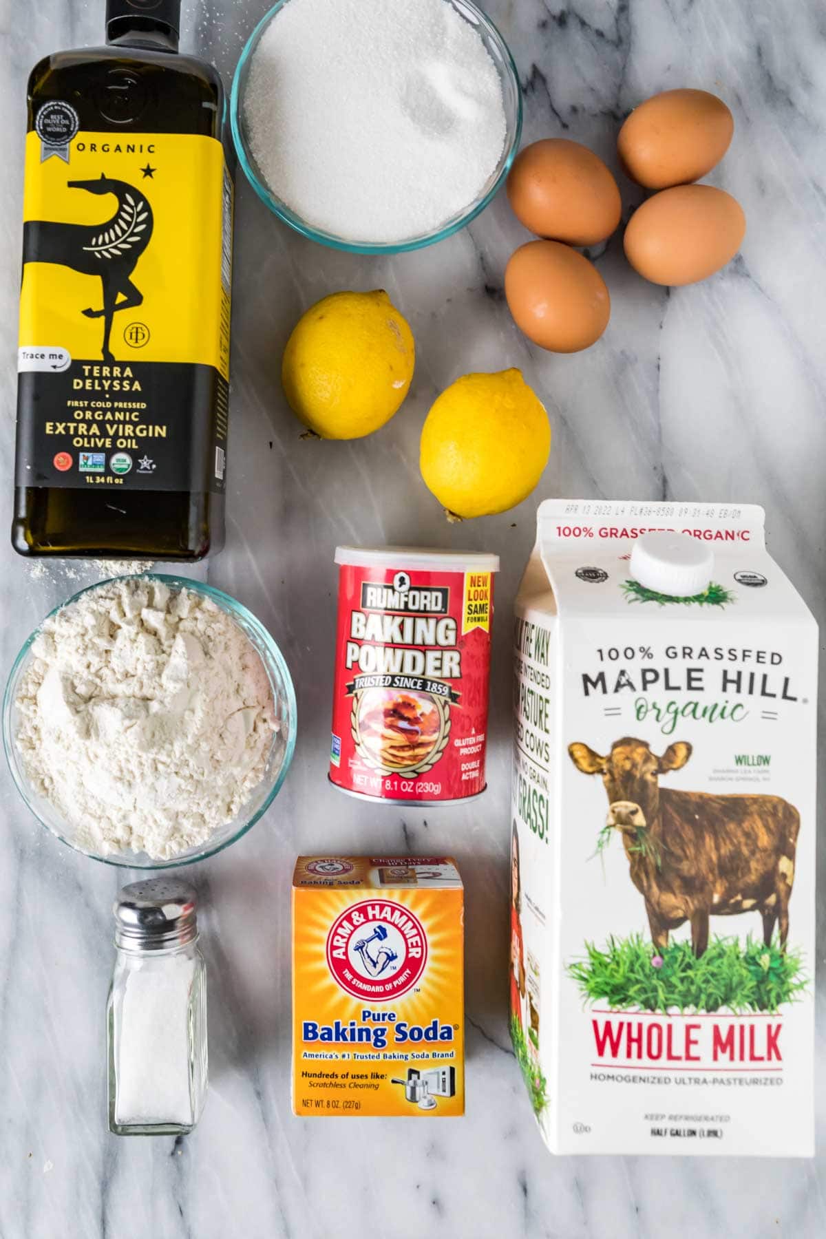 Overhead view of ingredients including lemons, olive oil, eggs, milk, and more.