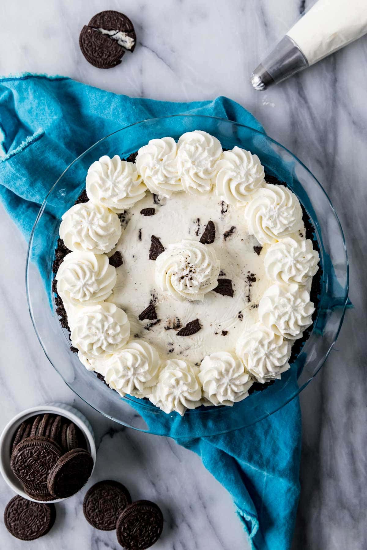 Overhead view of a pie made with Oreo crust, broken Oreo pieces, and a whipped cream topping.