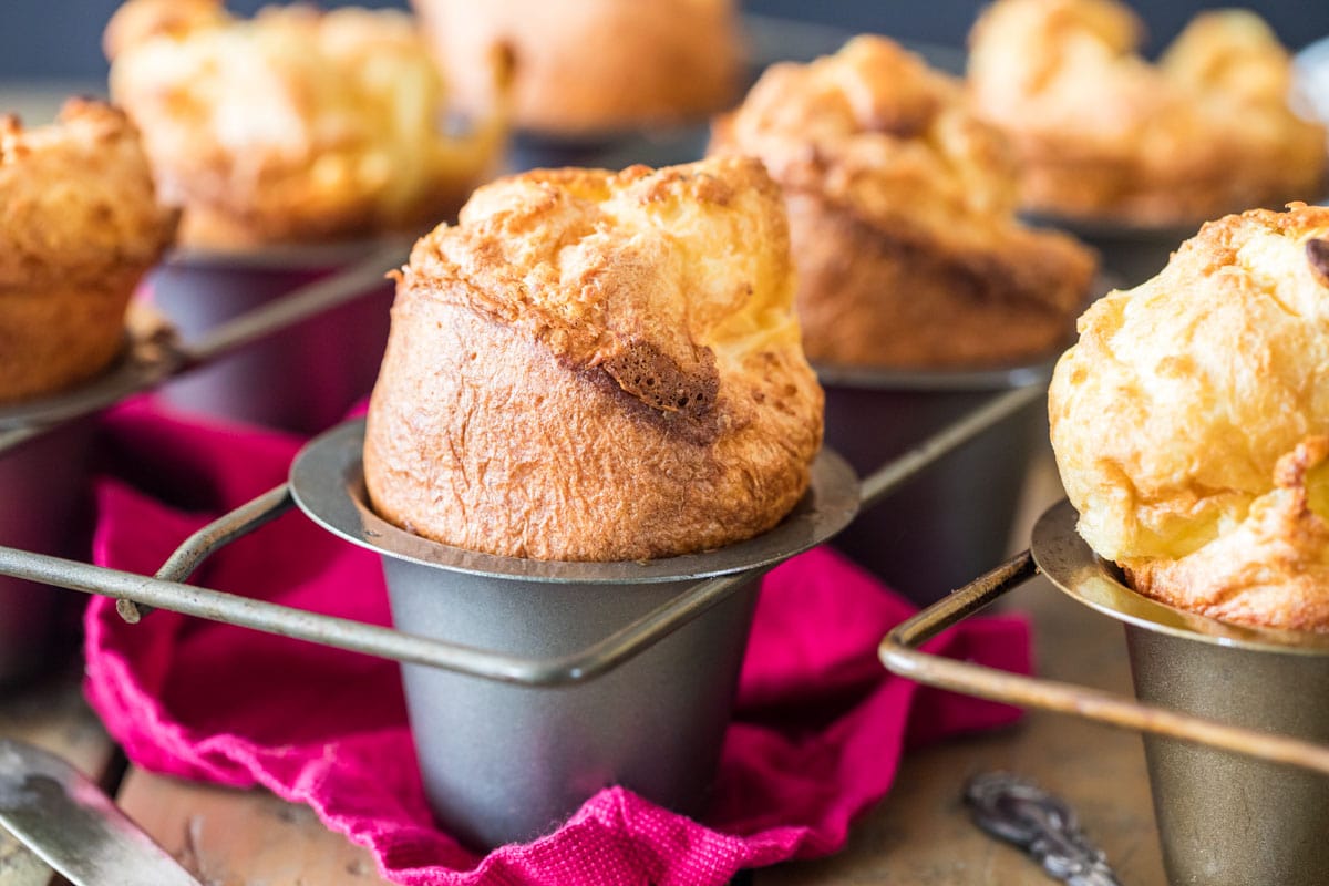 Pan of popovers with a fuchsia towel underneath.