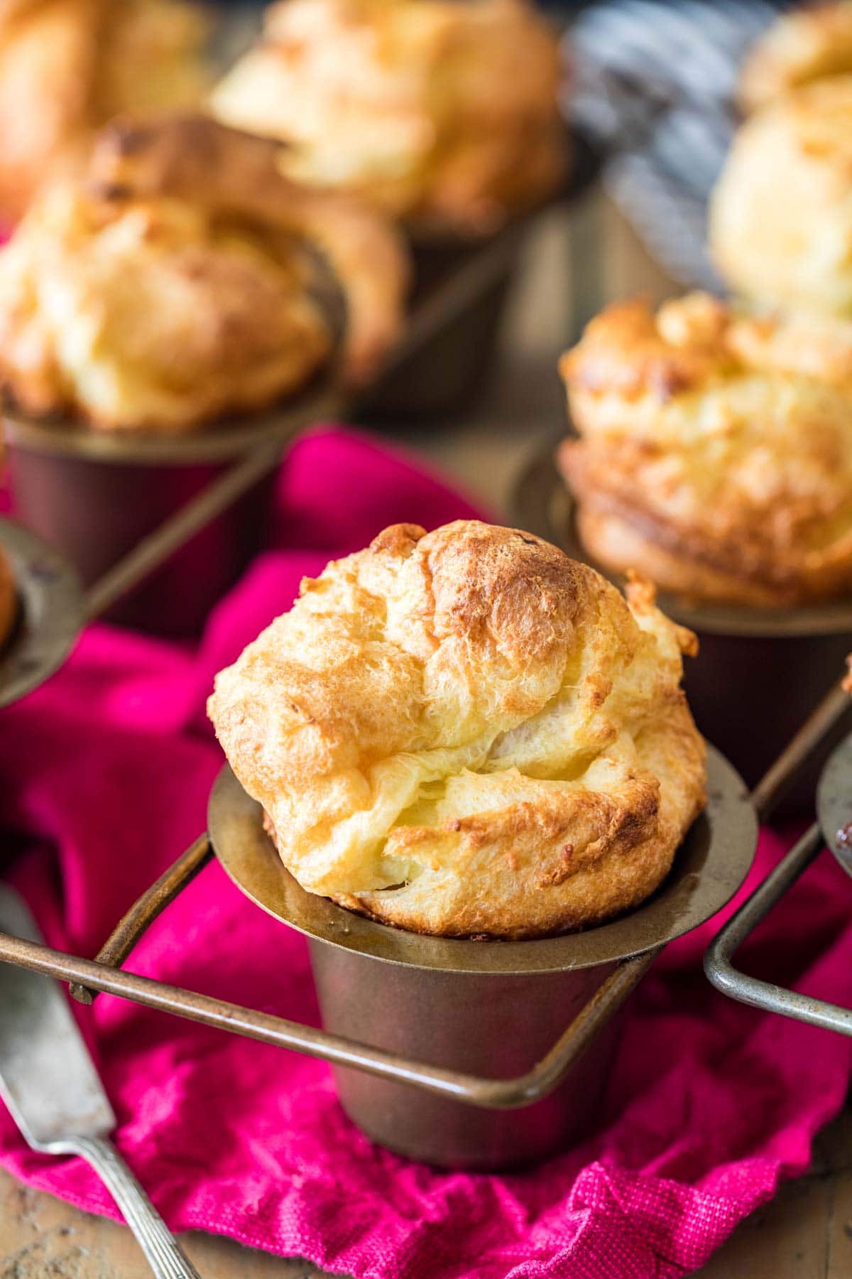 Pan of popovers with a fuchsia towel underneath.