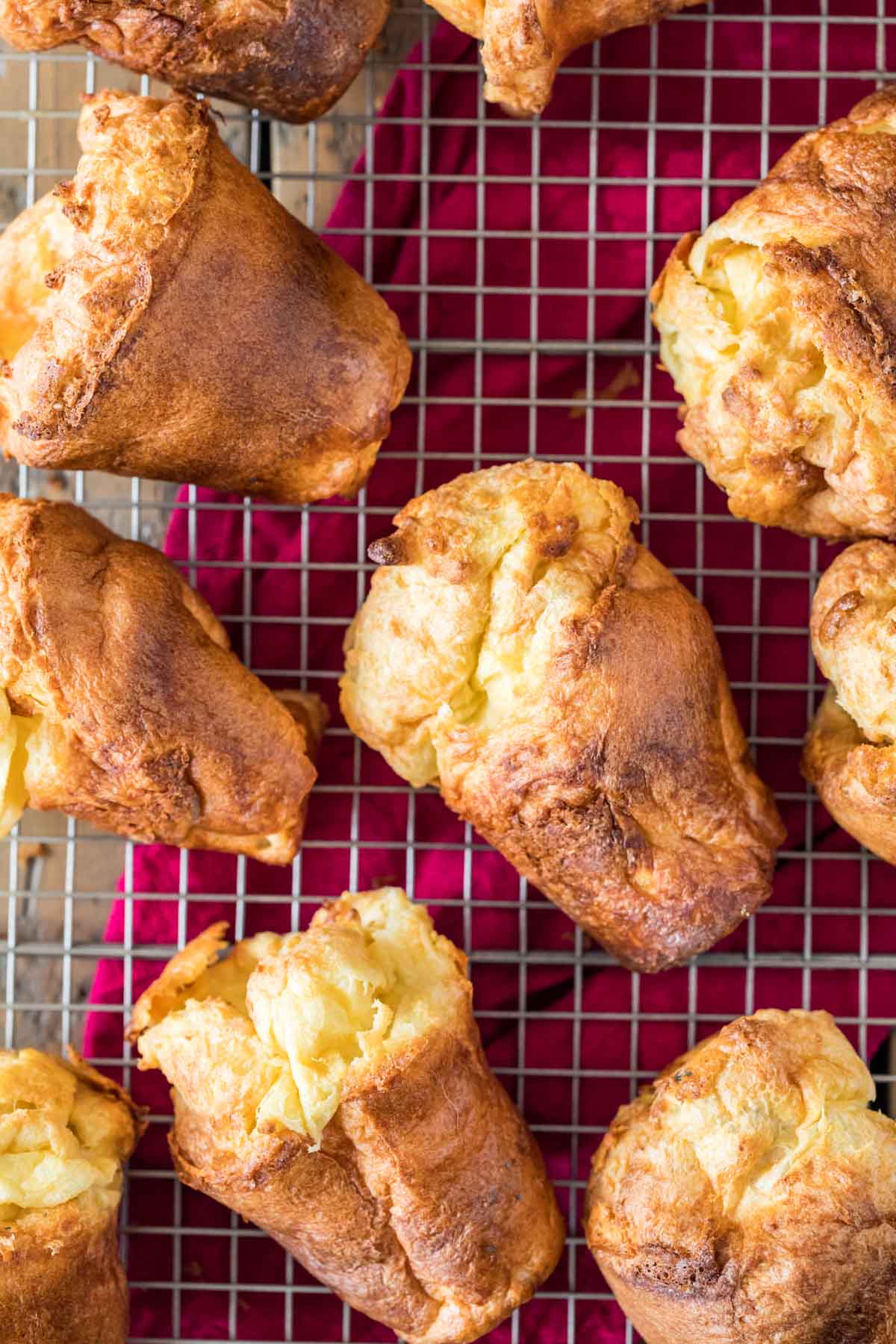 Popovers on a cooling rack with a fuchsia towel underneath.