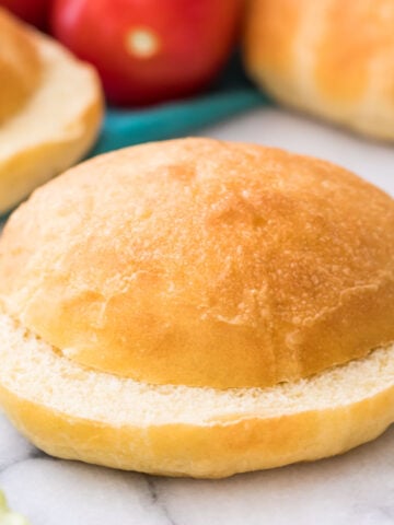 sliced potato bun on marble with lettuce and more buns in background