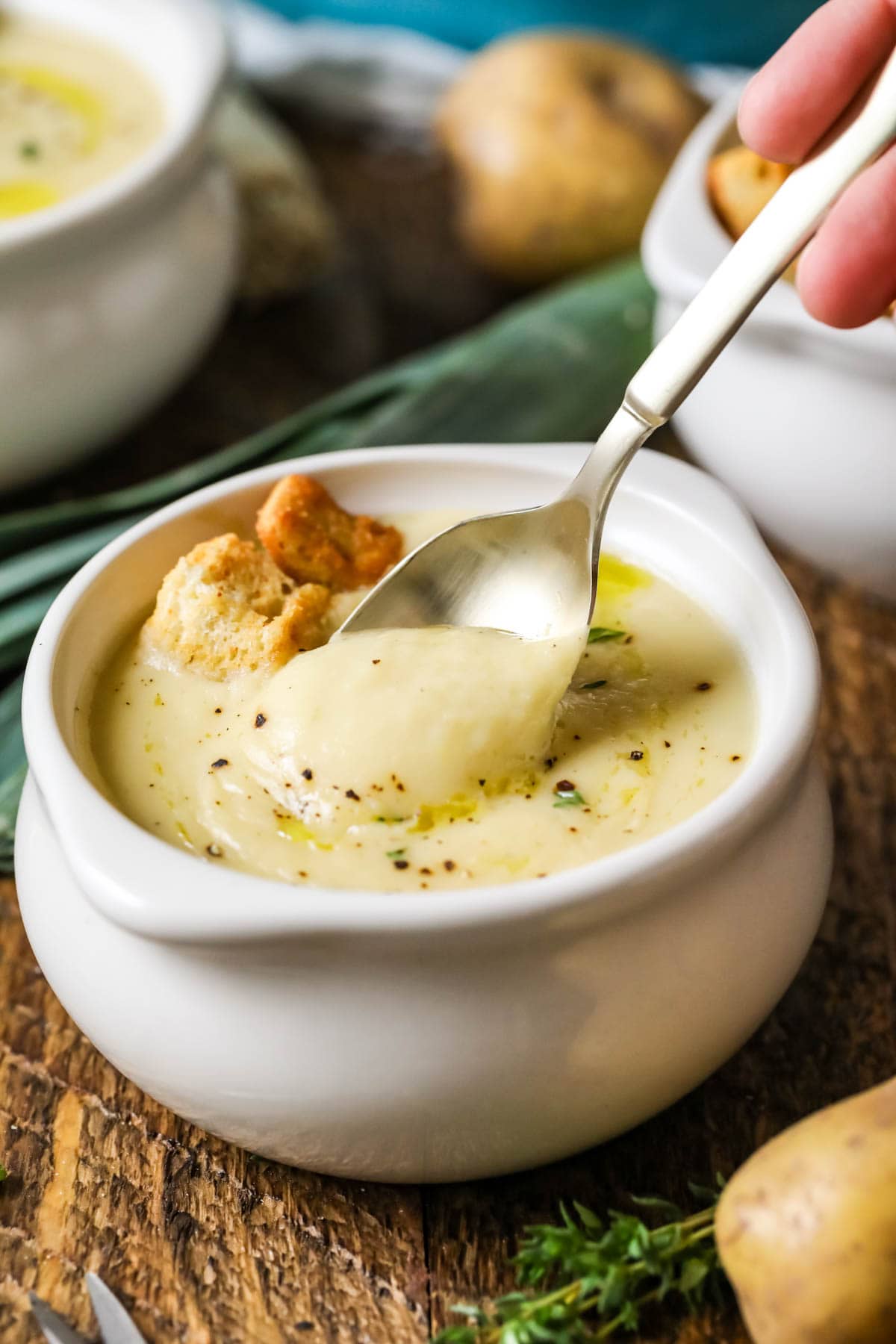 Spoon stirring potato leek soup in a small white crock.