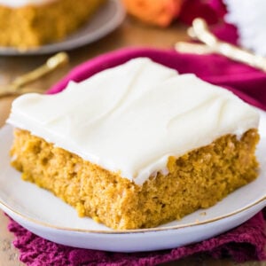 Pumpkin bar frosted with cream cheese frosting on a white plate.