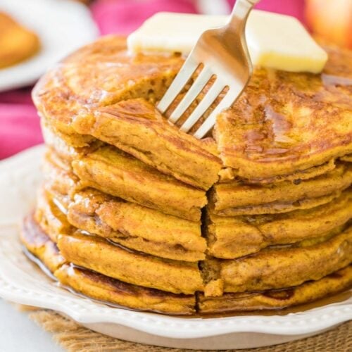 fork piercing a cut section from a stack of thick and fluffy pumpkin pancakes