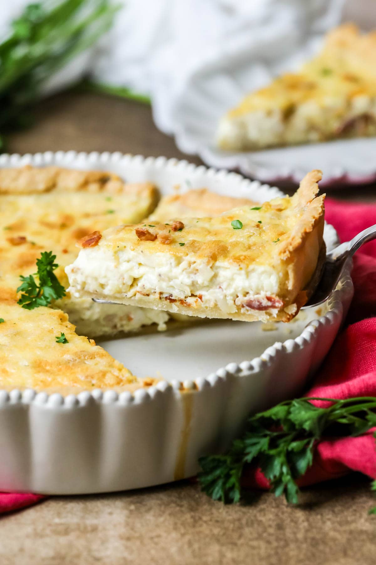 Slice of quiche lorraine being lifted out of the baking dish.