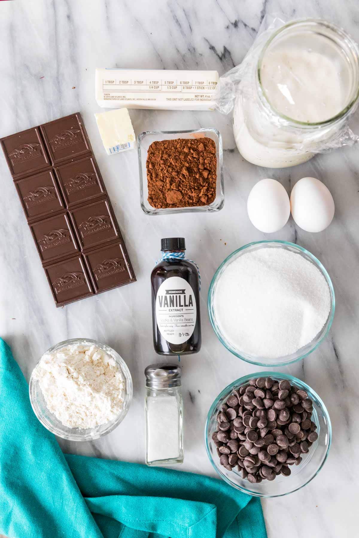 Overhead view of ingredients including a chocolate bar, cocoa powder, sourdough discard, and more.