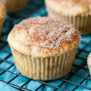 Cinnamon muffins on a cooling rack with a teal towel underneath.