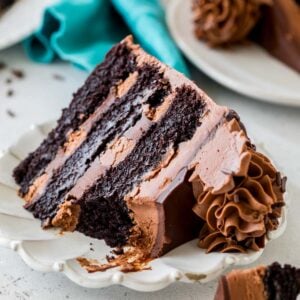 Slice of triple chocolate cake missing a bite on a white plate.